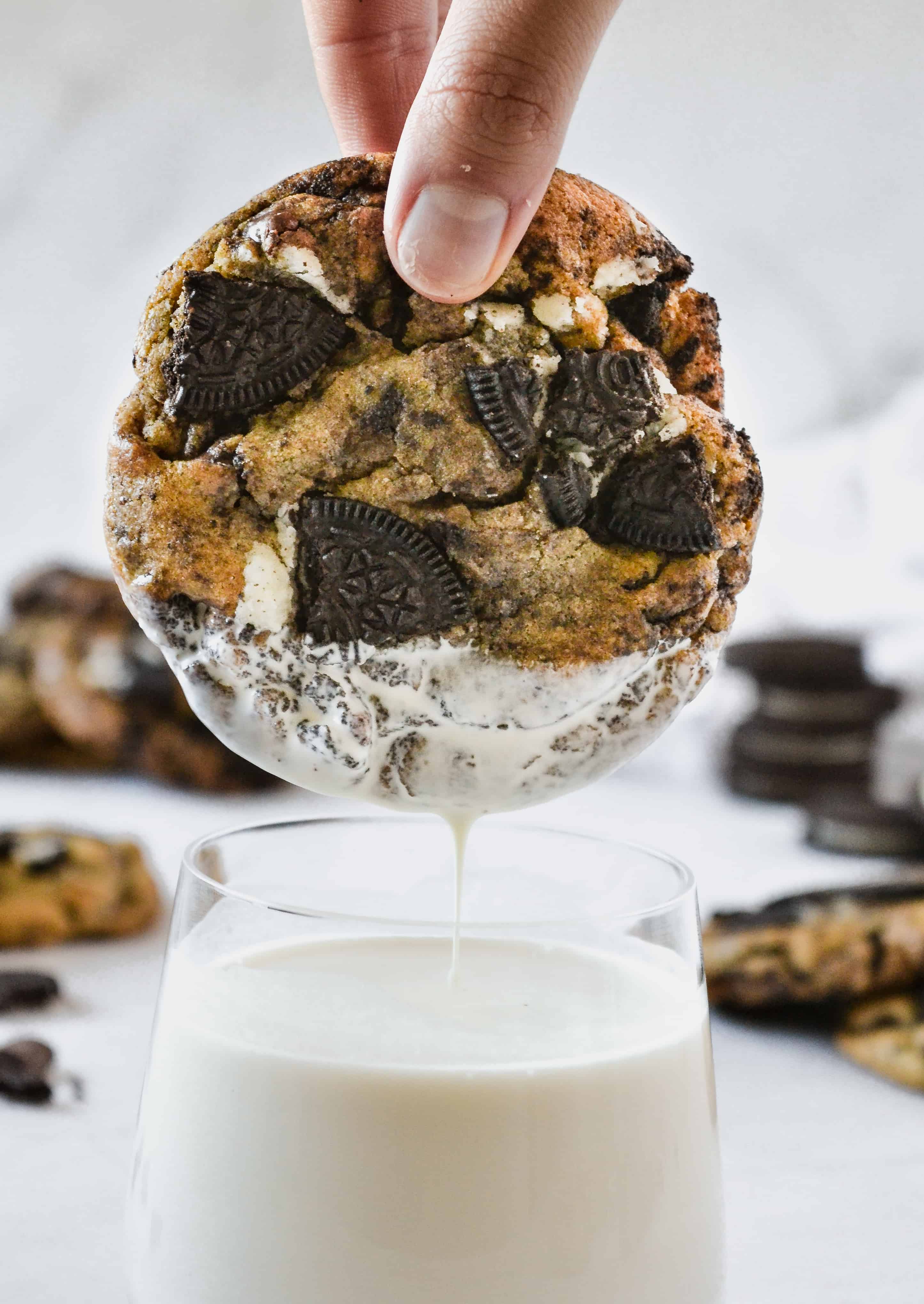 Crushed Oreo Chocolate Chip Cookies dipped in a glass of milk.